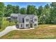 Two-story home with a long driveway, lush lawn, and mature trees, showcasing classic architectural style and curb appeal at 164 Meadow Glen Dr, Troutman, NC 28166