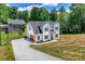 Aerial shot of a modern two-story home with an attached garage, a long driveway, and lush green surroundings at 164 Meadow Glen Dr, Troutman, NC 28166