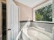 Bright bathroom featuring a soaking tub with a view and a white door at 16411 Greybriar Forest Ln, Charlotte, NC 28278