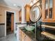 Bathroom featuring a vessel sink, dark countertops, wood cabinets, and an open door to the walk-in closet at 16411 Greybriar Forest Ln, Charlotte, NC 28278