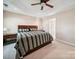 Comfortable bedroom with neutral carpet, ceiling fan, and a large bed with stylish striped bedding at 16411 Greybriar Forest Ln, Charlotte, NC 28278