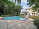 Backyard swimming pool featuring a tile border, concrete patio, and mature landscaping at 16411 Greybriar Forest Ln, Charlotte, NC 28278