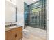 This bathroom features a wooden vanity, teal vertical tiling around the tub and a built in shower niche at 1830 Commodore St, Charlotte, NC 28205