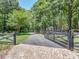 Gated driveway leading to a private estate surrounded by lush greenery and mature trees at 202 Walden Ln, Weddington, NC 28104
