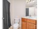 Traditional bathroom with a wooden vanity cabinet, toilet, and a shower with patterned curtain at 2100 Goddard Way, Waxhaw, NC 28173