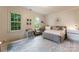 Bright, carpeted bedroom with two windows, a writing desk and chair, and a comfortable seating area at 4023 Alexandra Alley Dr, Charlotte, NC 28210