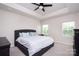 Bright bedroom features a tray ceiling, a ceiling fan, and plenty of natural light from the two windows at 411 Lahinch Dr, Tega Cay, SC 29708