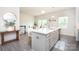 Open kitchen with white cabinets, stainless steel appliances, island seating, and access to the dining area at 411 Lahinch Dr, Tega Cay, SC 29708