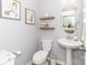 Stylish half bathroom features a pedestal sink, decorative shelves, a round mirror, and modern fixtures at 4268 Coachwhip Ave, Lancaster, SC 29720