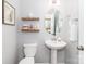 Stylish half bathroom features a pedestal sink, decorative shelves, a round mirror, and modern fixtures at 4268 Coachwhip Ave, Lancaster, SC 29720