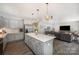 Open-concept kitchen flows into a living room, featuring a large island with quartz counters and pendant lighting at 5499 Angus Dr, Midland, NC 28107