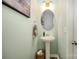 Stylish powder room with a pedestal sink, round mirror, and soft green walls at 5499 Angus Dr, Midland, NC 28107