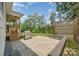 Landscaped backyard featuring a stone patio, grill, and lush greenery, perfect for outdoor living and entertainment at 7739 Village Pkwy, Locust, NC 28097