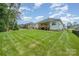 Expansive green backyard showcasing a covered deck and patio with lush lawn and mature trees, offering privacy at 7739 Village Pkwy, Locust, NC 28097