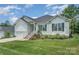 Inviting exterior showing manicured lawn and classic white siding detailing of the home with a two-car garage at 7739 Village Pkwy, Locust, NC 28097