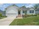 Charming home featuring a manicured lawn, brick stairs, and a two-car garage, set against a blue sky at 7739 Village Pkwy, Locust, NC 28097