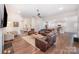 Open-concept living room featuring fireplace, hardwood floors, ceiling fan, and seamless flow to kitchen at 7739 Village Pkwy, Locust, NC 28097