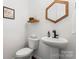 Contemporary half bathroom with a pedestal sink, decorative mirror, and sleek fixtures at 9547 Horsebit Ln, Concord, NC 28027