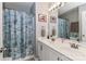 Well-lit bathroom featuring double sinks, seashell shower curtain, and neutral tones at 103 Pamlico Ln, Mooresville, NC 28117