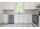 Bright kitchen featuring stainless steel appliances, white cabinets, marble floors, and a window above the sink at 110 College St, Marshville, NC 28103