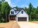 New construction two-story home featuring white siding, black trim, a two-car garage, and a charming front porch at 135 Brookview Dr, Shelby, NC 28152