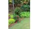 Lush backyard featuring beautiful landscaping, mature trees, vibrant flowerbeds, and well-maintained lawn at 13824 Glen Abbey Dr, Charlotte, NC 28278