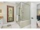 This luxurious bathroom features a glass enclosed shower with decorative accents, a walk-in closet, and white cabinets at 13824 Glen Abbey Dr, Charlotte, NC 28278