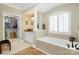 This luxurious bathroom features a large soaking tub with a large window, a walk-in closet, and tiled floors at 13824 Glen Abbey Dr, Charlotte, NC 28278