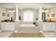 This luxurious bathroom features a large soaking tub with a large window, dual vanities, and decorative art at 13824 Glen Abbey Dr, Charlotte, NC 28278