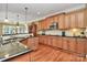 Well-lit kitchen featuring hardwood floors, granite countertops, and wood cabinets with modern stainless steel appliances at 13824 Glen Abbey Dr, Charlotte, NC 28278