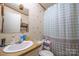 Bathroom with a white sink and toilet plus blue polka-dotted shower curtain and brown shelving at 1495 Leonards Fork Church Rd, Lincolnton, NC 28092