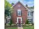 Charming brick townhouse featuring a red front door, black shutters, and manicured landscaping at 1735 Robinwood Rd, Gastonia, NC 28054