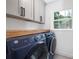 Modern laundry room with front load washer, dryer, wood countertop, and storage cabinets at 2120 Shadyview Dr, Charlotte, NC 28210
