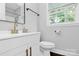 Modern bathroom features a white vanity with gold fixtures and a large window for natural light at 3909 Woodbriar Trl, Charlotte, NC 28205