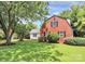 A charming two-story home has a red brick exterior, a well-maintained lawn, and mature trees at 3909 Woodbriar Trl, Charlotte, NC 28205