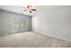 This bedroom features neutral walls, carpet, a ceiling fan, and two windows at 4507 Mackinac St, Charlotte, NC 28269