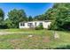 Single-story home featuring a cozy front porch, simple landscaping and mature trees at 4905 Grassy Creek Rd, Denver, NC 28037