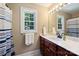 Bright bathroom features a vanity with wood cabinets, a sink, mirror, and a window at 6309 Chamar Cir, Kannapolis, NC 28081