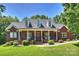 Inviting brick home featuring a covered front porch, manicured lawn, and mature trees at 6309 Chamar Cir, Kannapolis, NC 28081