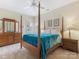 Bright bedroom featuring a four-poster bed, wooden furniture, and neutral decor at 8918 Cotton Press Rd, Charlotte, NC 28277