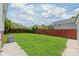 Green backyard surrounded by a red fence and adjacent properties under a blue, cloudy sky at 1113 W 4Th Ave, Gastonia, NC 28052