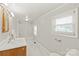 Bright bathroom featuring a shower-tub combo, tiled floor, and a sink with wood cabinet and window at 1113 W 4Th Ave, Gastonia, NC 28052