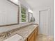 Bathroom featuring double sinks, a granite countertop, framed mirrors, and a window that overlooks a lush garden at 1119 Holleybank Dr, Matthews, NC 28105