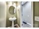 Powder room featuring a pedestal sink, round mirror and neutral color scheme, adjacent to the foyer at 13916 Mallard Lake Rd, Charlotte, NC 28262