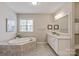 Bright bathroom featuring an oval bathtub, tiled surround, double sinks, and a large window at 16016 Reynolds Dr, Fort Mill, SC 29707