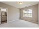 Bright, neutral bedroom with large window and view into en suite bathroom at 16016 Reynolds Dr, Fort Mill, SC 29707
