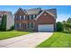 A two-story brick home showcasing a long driveway, lush lawn, and attached garage at 2117 Copperplate Rd, Charlotte, NC 28262