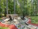 Serene backyard featuring a stone patio, a fire pit, and surrounded by lush greenery and mature trees at 3227 Cape Fox Ct, Denver, NC 28037