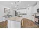 Bright kitchen boasts white cabinets, stainless steel appliances, an island, and wood floors at 3317 Black Cherry Dr, Monroe, NC 28110
