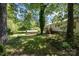 Lush backyard featuring mature trees, green lawn, a deck, and storage shed on a sunny day at 38367 Loblolly Ln, New London, NC 28127